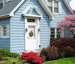 GettyImages-450671313 Blue house with vibrant garden and door.