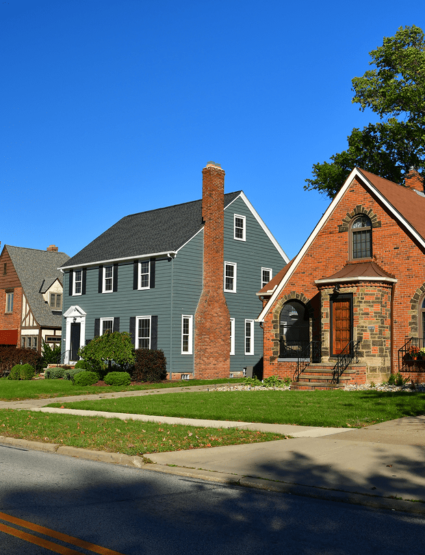 GettyImages-918361830 Two suburban houses under clear blue sky.